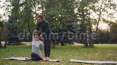 斯利姆女孩瑜伽教练正在帮助她的<strong>学生</strong>在秋季公园的个人练习中<strong>管理</strong>Gomukhasana。